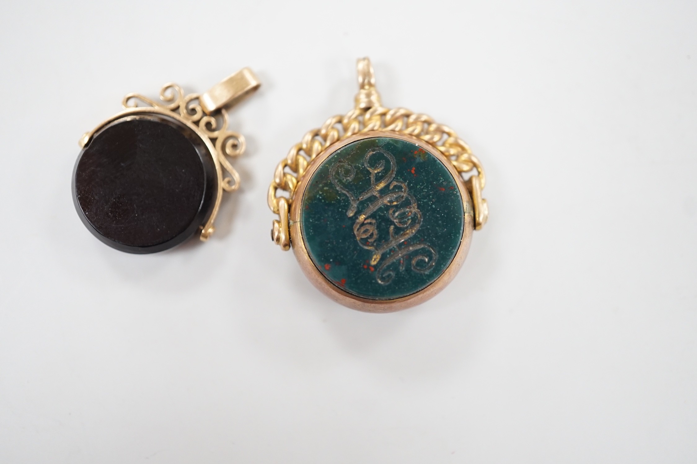 A late Victorian 9ct gold and bloodstone set spinning fob seal, 29mm and one other yellow metal and chalcedony set spinning fob seal.